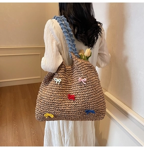 Detail of straw woven tote with colorful bows and blue ruffled strap on a model