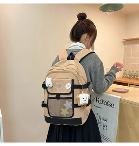 Detail of beige and black backpack with cute plush rabbit charms and star patches