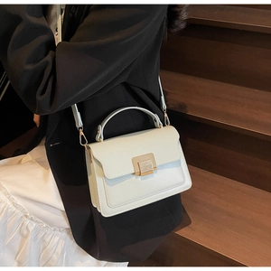 Detail of light blue crossbody bag with gold buckle on a model in urban setting