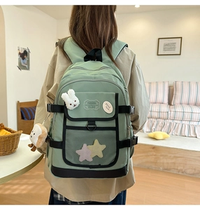 Close-up of green nylon backpack with cute plush bunny pins and star patches