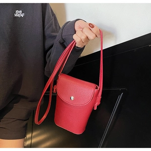 Detail of red pebbled leather crossbody bag with metal ring buckle and magnetic flap