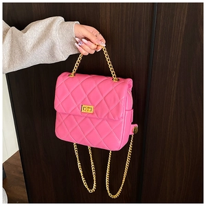 Détail d'un sac à main rose matelassé avec chaîne dorée et fermoir rotatif métallique