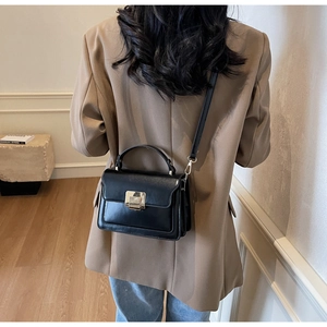 Detail of black leather crossbody bag featuring silver square metal clasp and top handle