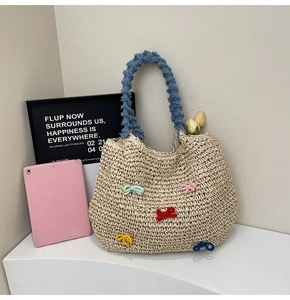 Close-up of beige woven straw tote bag with blue handles and colorful bow details