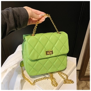 Détail d'un sac vert matelassé avec poignée en chaîne dorée et fermoir rotatif