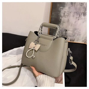Detail of grey pebbled leather handbag with chain handle and pearl heart charm