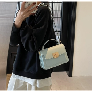 Detail of light blue crossbody bag with gold metal buckle shown on a model