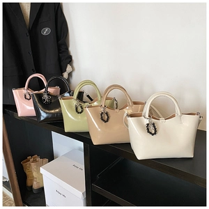 Row of colorful glossy patent leather tote bags with elegant pearl charms on display