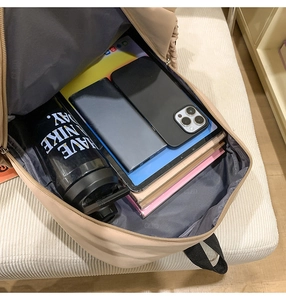 Detail showing high-capacity interior of beige backpack with tablet and notebooks