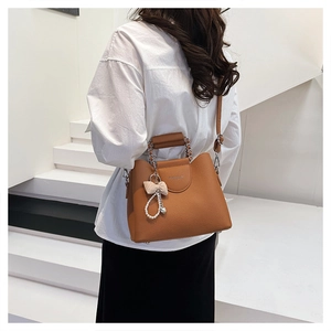 Brown lychee grain handbag featuring a pearl butterfly charm and gold chain strap detail
