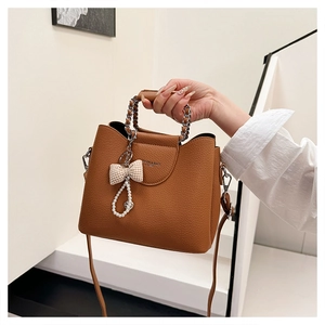 Detailed texture of brown pebble leather handbag with gold chain and bow accessory