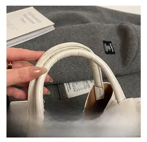 Detail of soft padded white leather handle with silver metal buckles on a tote bag
