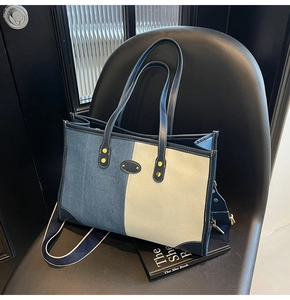 Dettaglio della borsa tote in tela bicolore con manici in pelle su una sedia in pelle