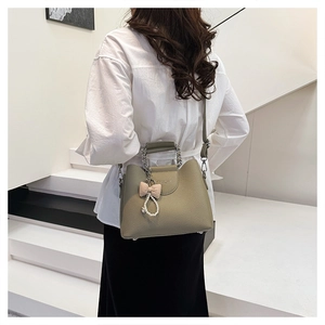 Litchi texture leather handbag detail with pearl charm and checkered bow accessory