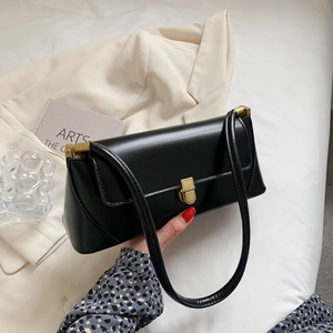 Minimalist black baguette shoulder bag with gold metal buckle and leather strap