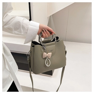 Detail of green lychee leather handbag with silver chain handle and pearl bow charm