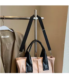 Detail of pink crossbody bag with black nylon straps and smooth silver metal buckles