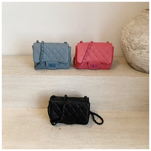 Close-up of three quilted chain bags in blue, pink, and black colors on stone steps