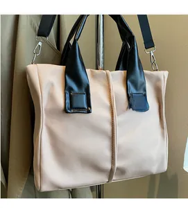 Detail of apricot crossbody bag with black leather handles and adjustable wide nylon strap