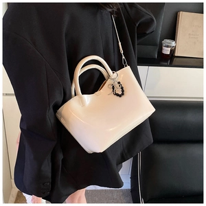 Chic cream white glossy handbag shown on shoulder in a modern lifestyle setting