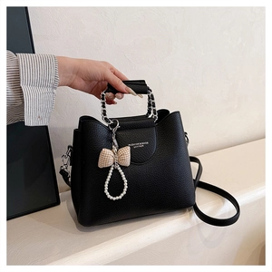 Close-up of black litchi pattern leather handbag with chain handle and pearl charm