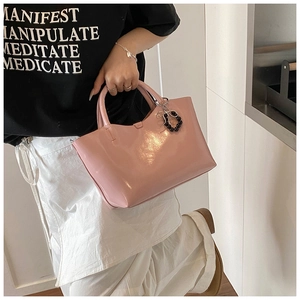 Detailed macro view of pink patent leather handbag featuring a black beaded bow charm