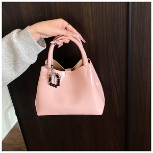 Close-up of pink PU leather handbag with silver bow pendant and black beads