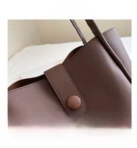 Détail du fermoir magnétique et de la boucle ronde sur un sac cabas en cuir PU brun