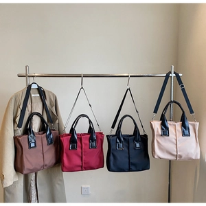Detail of four colored nylon tote bags in coffee, red, black, and beige with leather handles