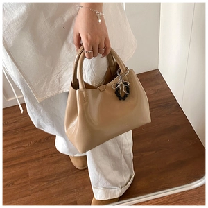 Detail of khaki PU tote bag with elegant silver bow charm and black beaded pendant