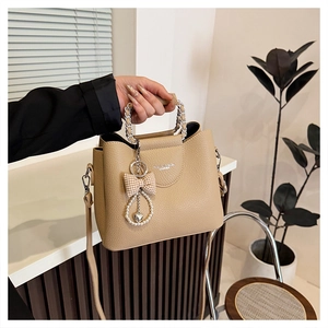 Detail of beige litchi grain tote with silver chain handle and bow pearl charm