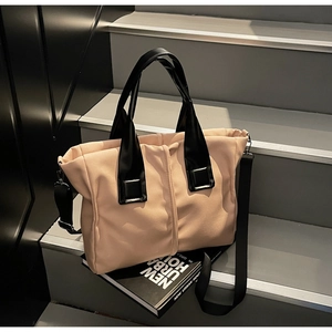 Detail of pink fabric tote bag with black leather handles and textured pleated surface