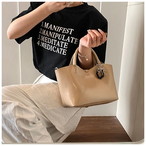 Detail of beige leather handbag featuring a stylish black bead and metal bow charm
