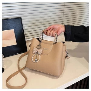 Detail of lychee pattern leather handbag with chain handle and bow charm decoration