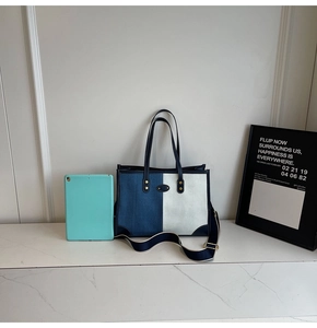 Borsa tote in tela bicolore con finiture in pelle accanto a un tablet per misura
