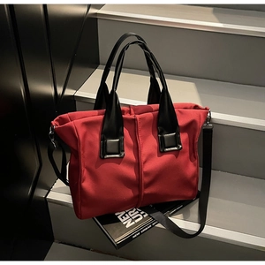 Detailed view of red contrast tote bag with black glossy straps on urban stairs