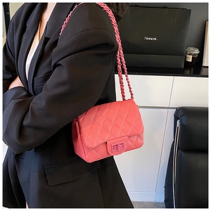 Detail of pink quilted leather crossbody bag with chain strap on a black suit jacket