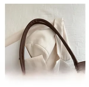 Détail de la poignée en cuir marron foncé ornée d'un foulard en soie à motifs chic