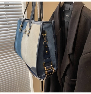 Dettaglio della borsa tote in tela blu e beige con manici in pelle e tracolla con borchie