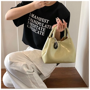 Detail of glossy light green patent leather handbag with silver bow charm and beaded handle