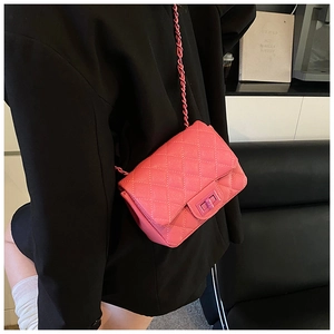 Detail of pink quilted flap bag with matching chain strap on a black blazer outfit