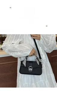 Detail of black leather square bag with silk scarf handle and metal clasp closure