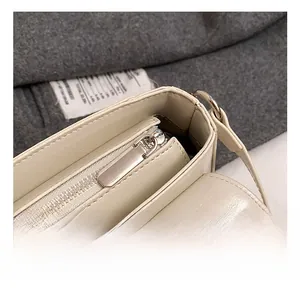 Detail of beige saddle bag with high-quality metal zipper and leather texture