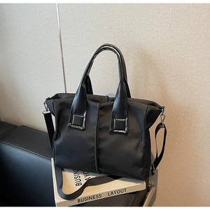 Detail of black nylon tote bag with leather handles and adjustable shoulder strap