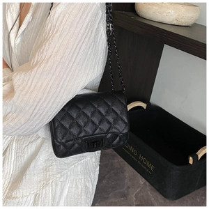 Close-up of black quilted leather shoulder bag with a vintage chain strap and metal lock