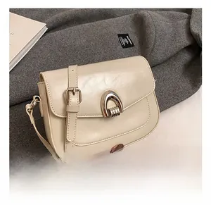 Detail of cream saddle bag with a metallic horseshoe buckle and premium faux leather texture