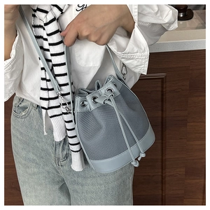 Mannequin portant un sac seau à cordon bleu clair avec patchwork en maille et cuir