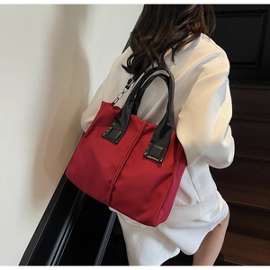 Detailed view of a red nylon tote bag with black leather handles and center seam design