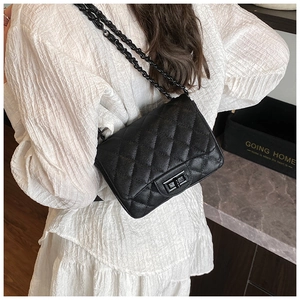 Detail shot of the black quilted leather texture and metallic chain strap on a flap bag