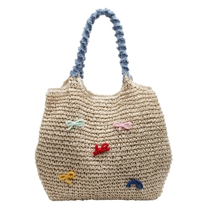 Straw beach tote bag with colorful bows and light blue ruffled handle on white background